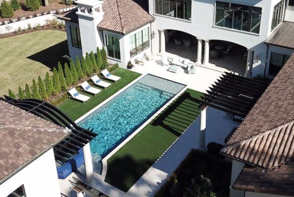 Luxury home with modern pool, lounge chairs, and landscaped backyard. Ideal for outdoor relaxation.