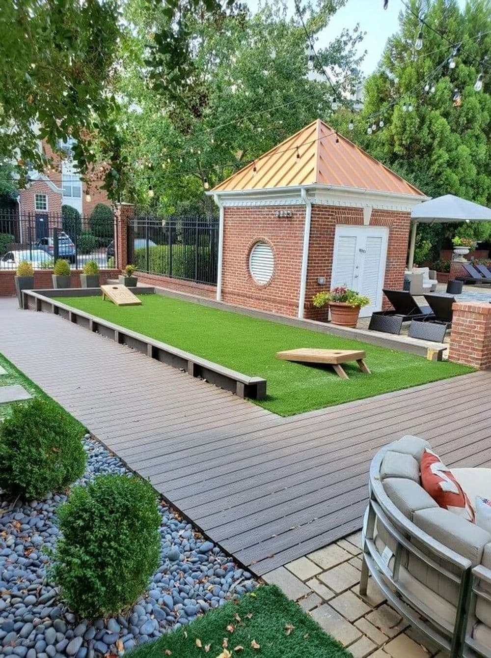 Modern backyard design with artificial grass, wooden deck, and stylish seating area.