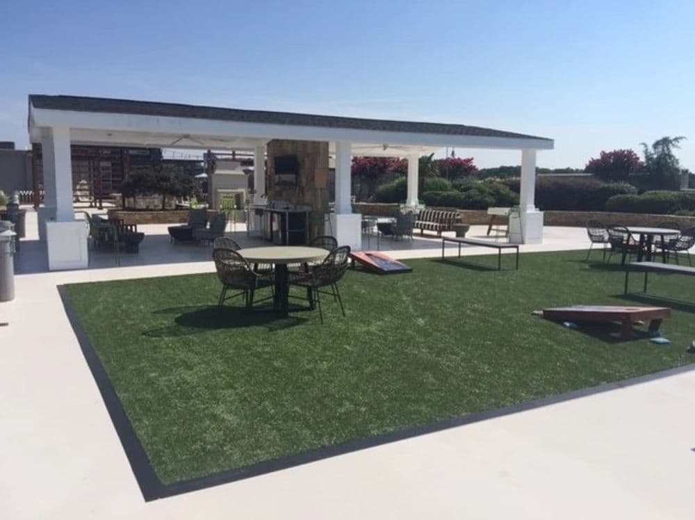 Rooftop lounge area with artificial grass, seating, and grill for outdoor gatherings.
