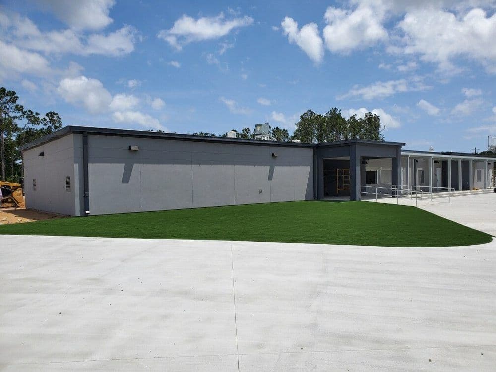 Modern commercial building with landscaped lawn and blue sky in the background.