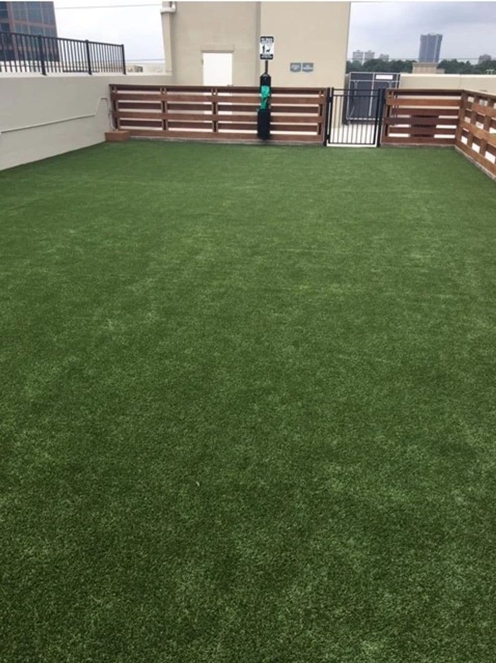 Rooftop dog park with artificial grass and a fence, ideal for pet exercise and play.
