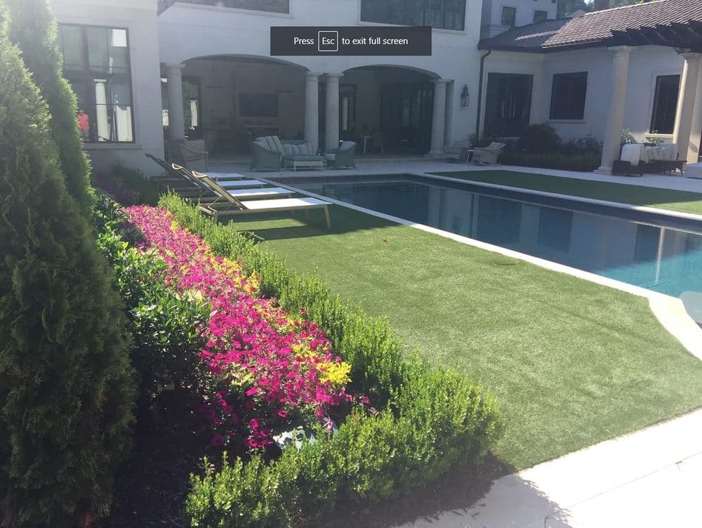 Vibrant floral garden by a modern poolside with lounge chairs and patio seating.