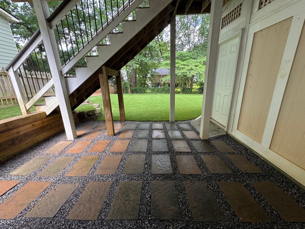 Stone pathway under stairs with gravel and grassy backyard visible. Outdoor design elements.