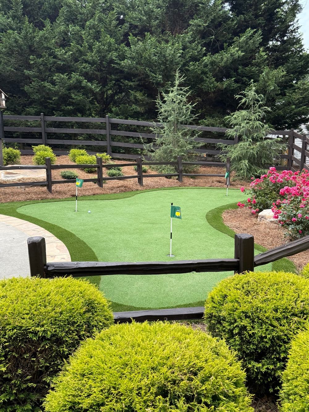 Home putting green with flags, surrounded by lush greenery and vibrant flowers.