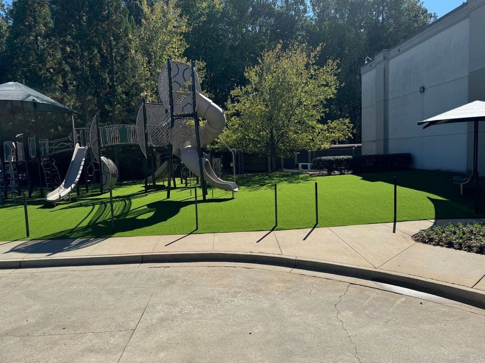 Playground area featuring slides and green turf under sunny skies, ideal for outdoor activities.
