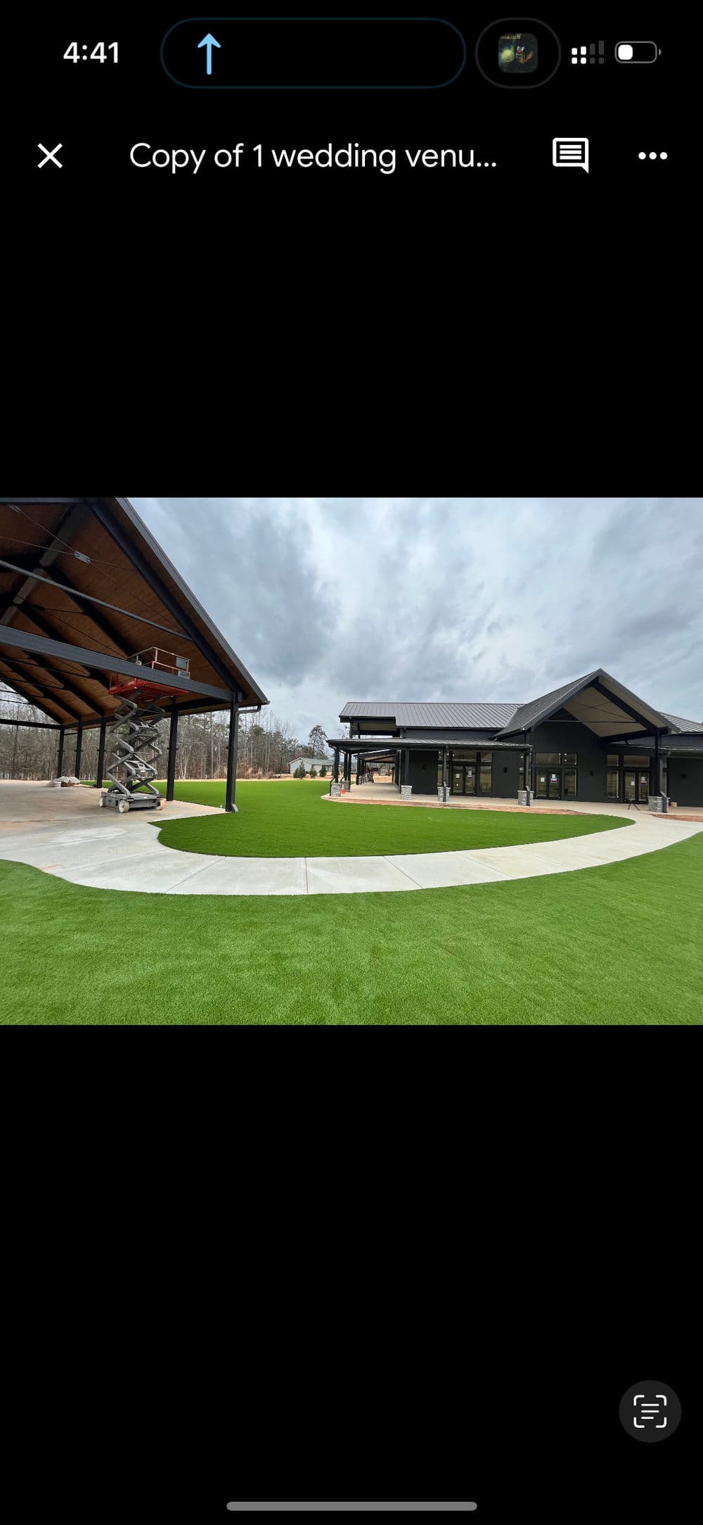 Modern wedding venue with lush green lawn and contemporary architecture under cloudy sky.